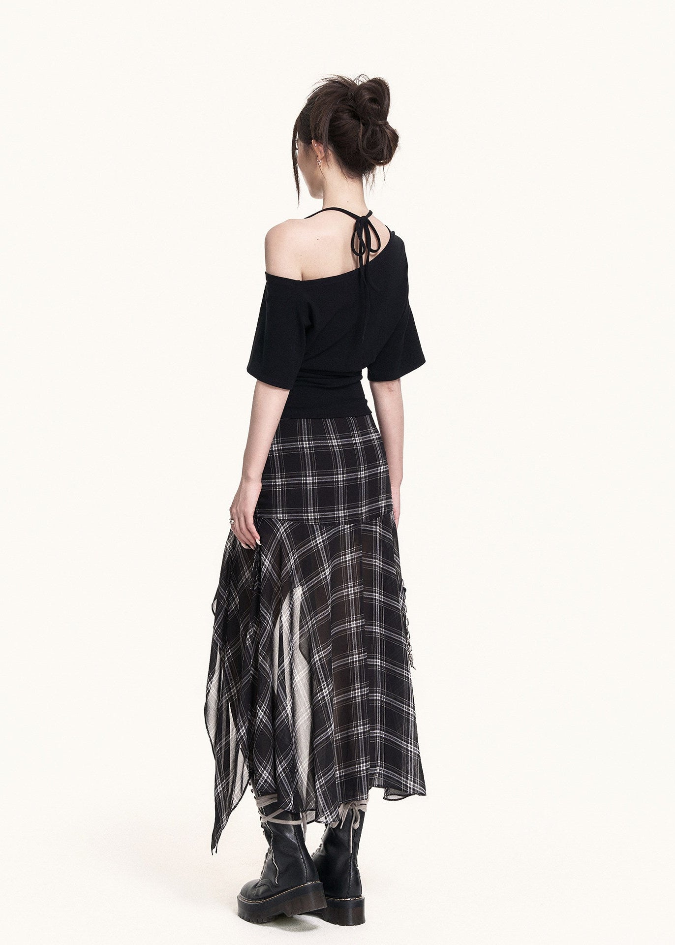 Black cross-shoulder tee styled with a plaid skirt